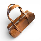 Brown leather bowler style bag with a strap on a white background. The image is from above and shows the detailing at the top of the bag, the zipper pulls and the straps
