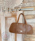 Brown handbag hanging on a wooden door with a chandelier in the foreground
