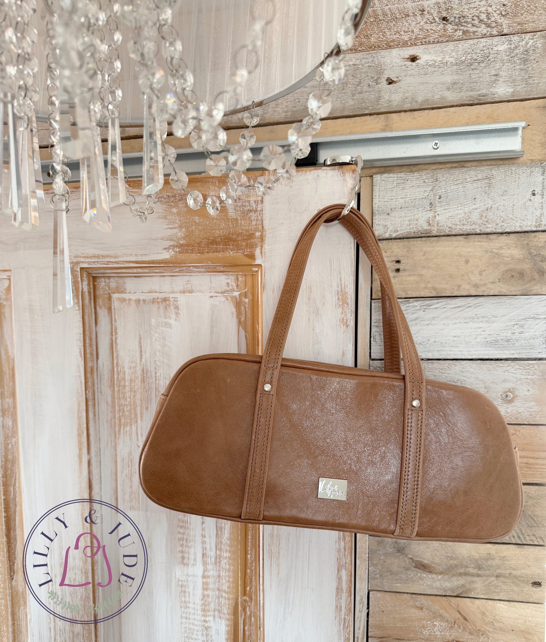 Brown handbag hanging on a wooden door with a chandelier in the foreground