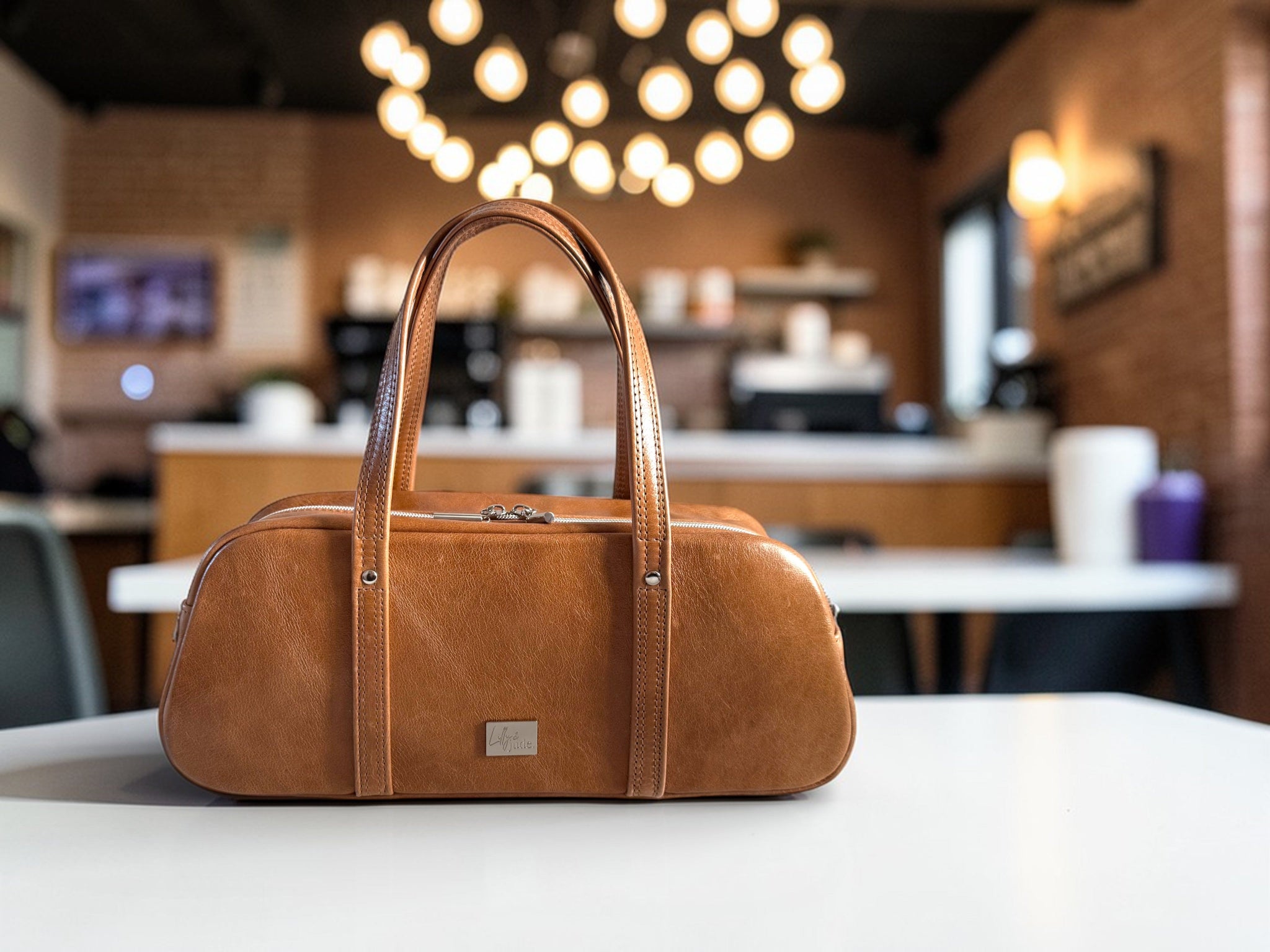 Tan coloured, rescued leather bowler handbag on a table with a blurred cafe background