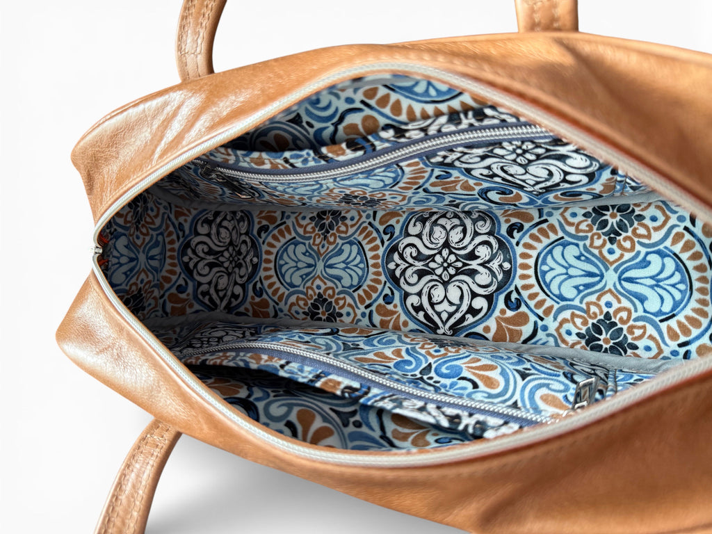 Brown leather handbag with blue and white patterned interior on a white background