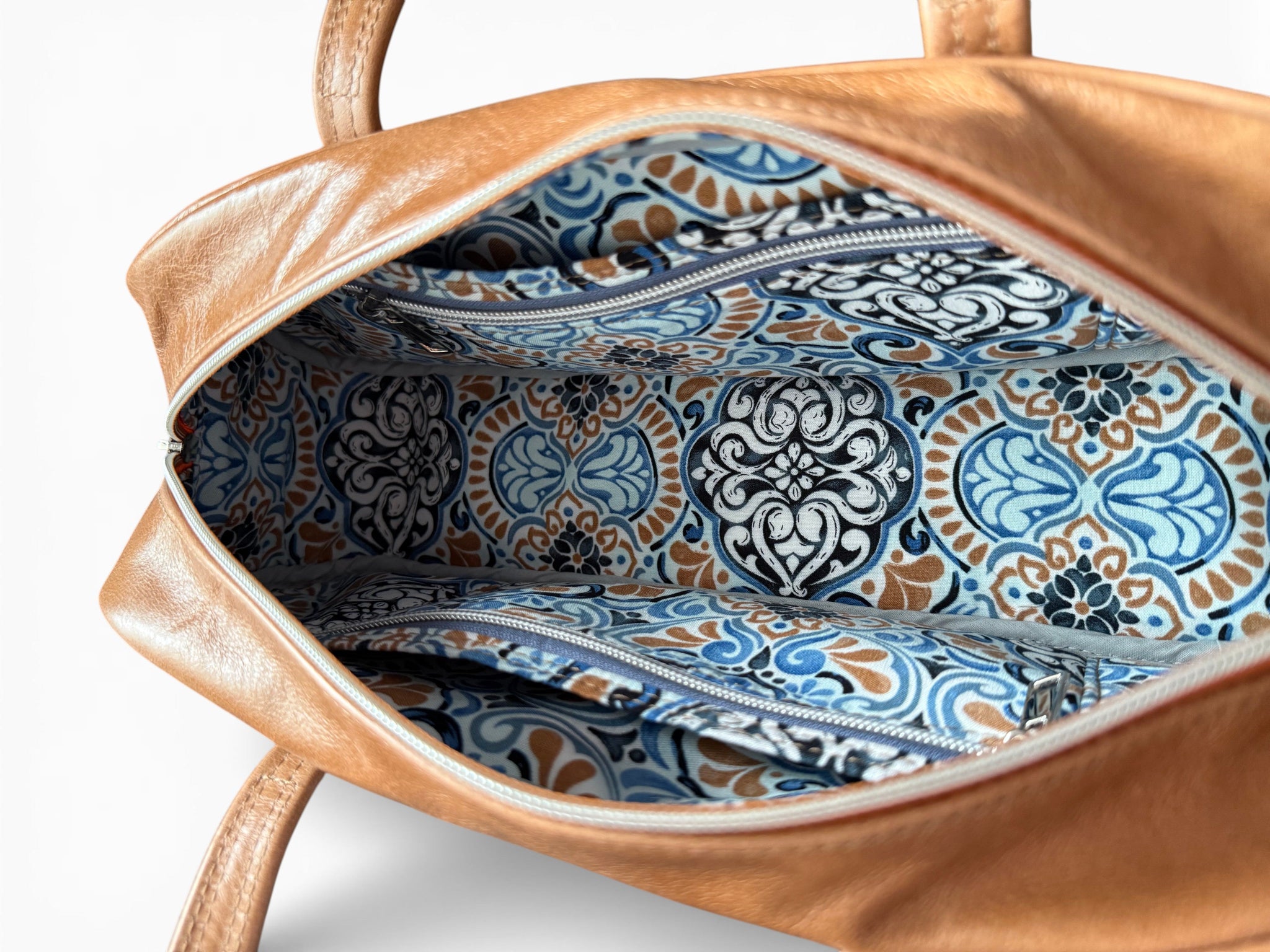 Brown leather handbag with blue and white patterned interior on a white background