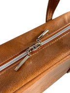 Brown leather handbag with a silver zipper and pulls on a white background