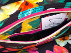 Closeup view of the interior of the Catalina bag. The image shows the lining fabric and the open slip/zip pocket, which contains a hidden integrated purse. Colorful floral-patterned bag with a visible brand tag.
