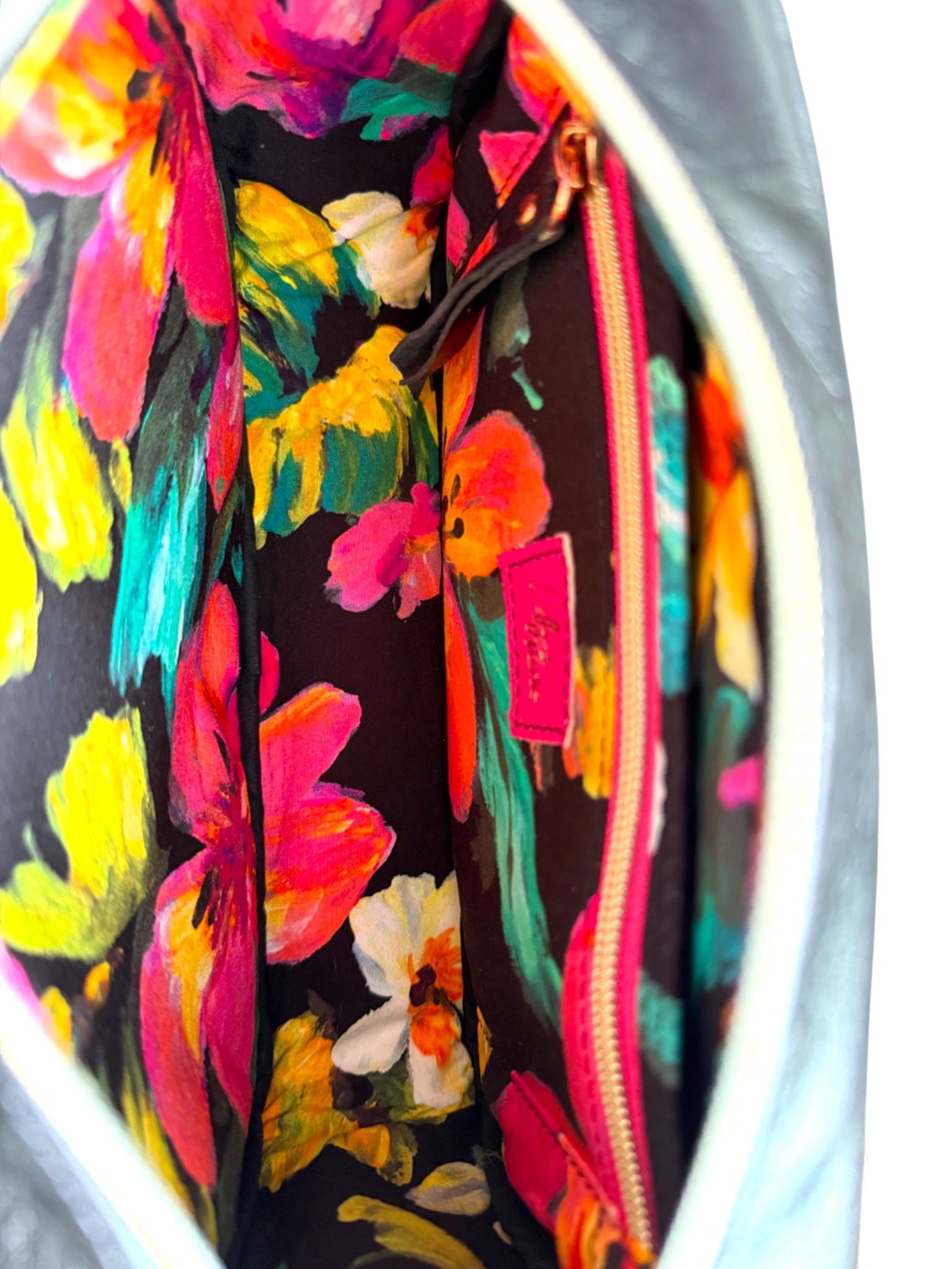 Interior view, to show the floral-patterned lining of the bag with a visible Lilly and Jude logo and the slip/zip pocket