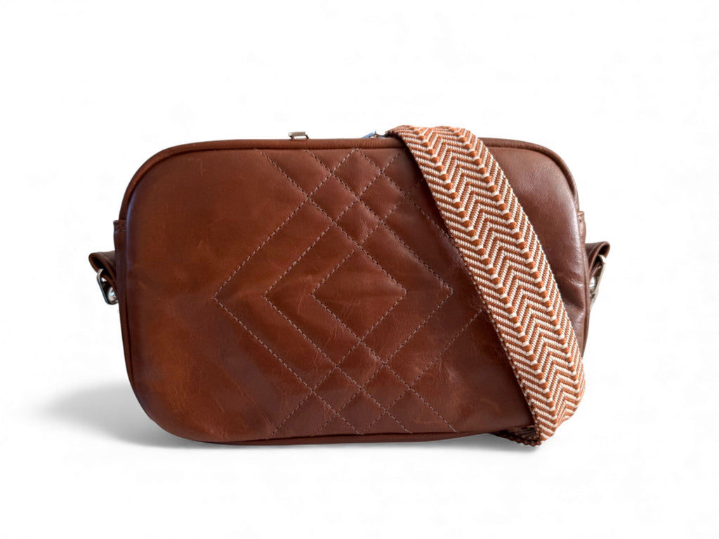 Brown quilted leather crossbody bag with a herringbone pattern strap on a white background