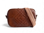 Brown quilted leather crossbody bag with a herringbone pattern strap on a white background