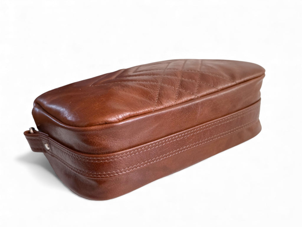 View of the underside of the brown leather Catalina cross body bag. It shows the under strap and the texture of the leather