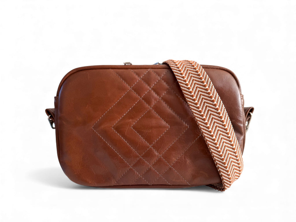 Brown quilted handbag with a herringbone patterned strap on a white background