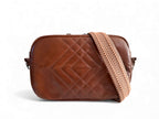Brown quilted handbag with a herringbone patterned strap on a white background