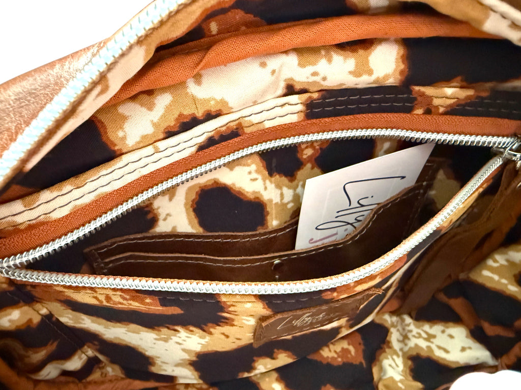 View of the interior of the brown leather Catalina bag, showing the leopard print lining and the slip/zip pocket open to reveal the integrated purse 