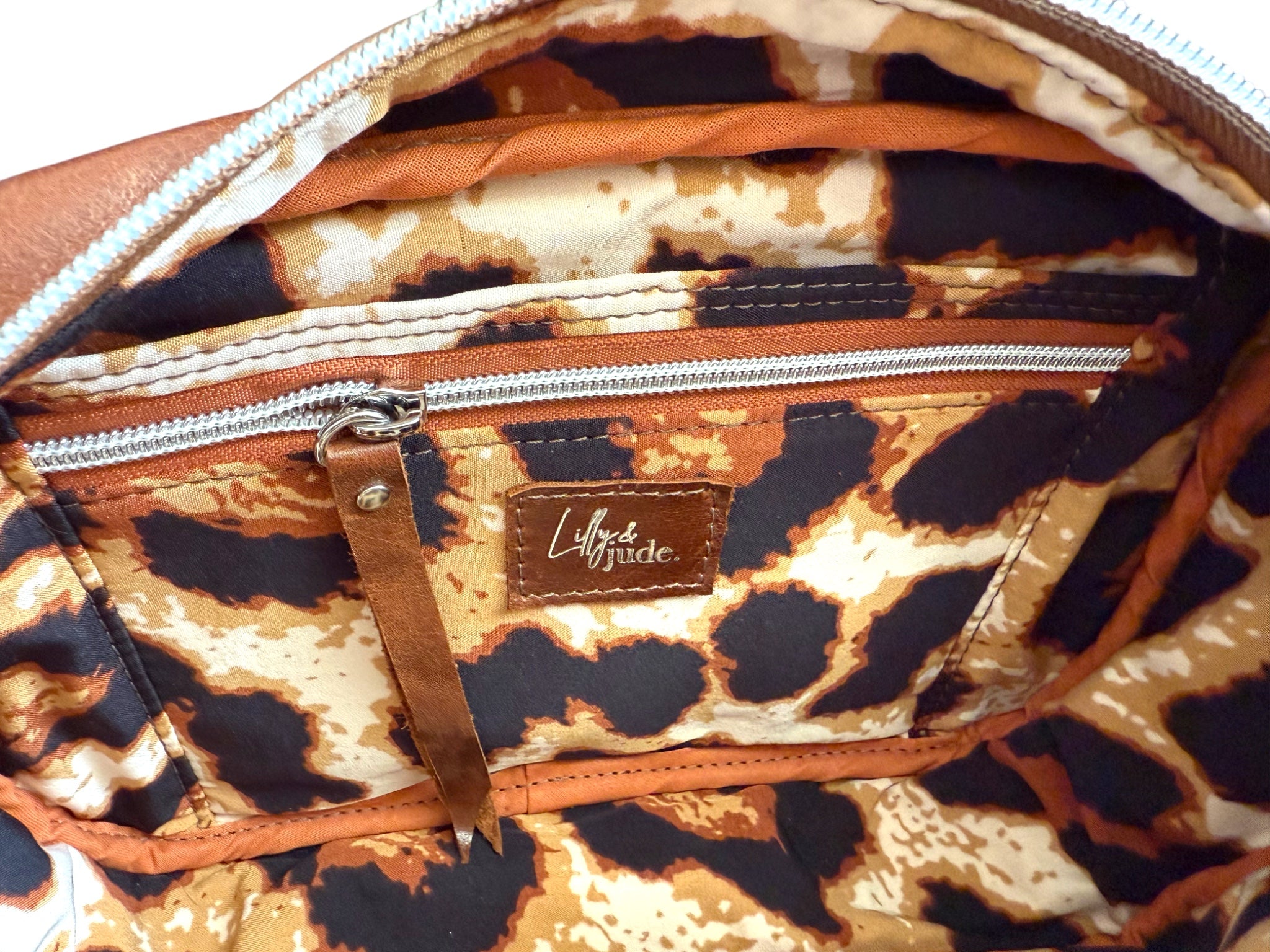Leopard print lining of the Catalina crossbody bag and the interior slip / zip pocket, with a visible brand label on a white background