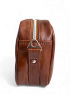 View of the side of the brown leather Catalina crossbody, with a silver zipper and hardware, on a white background