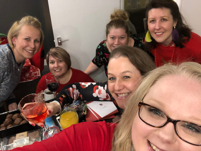 Group of women posing together at a festive gathering with drinks and decorations.