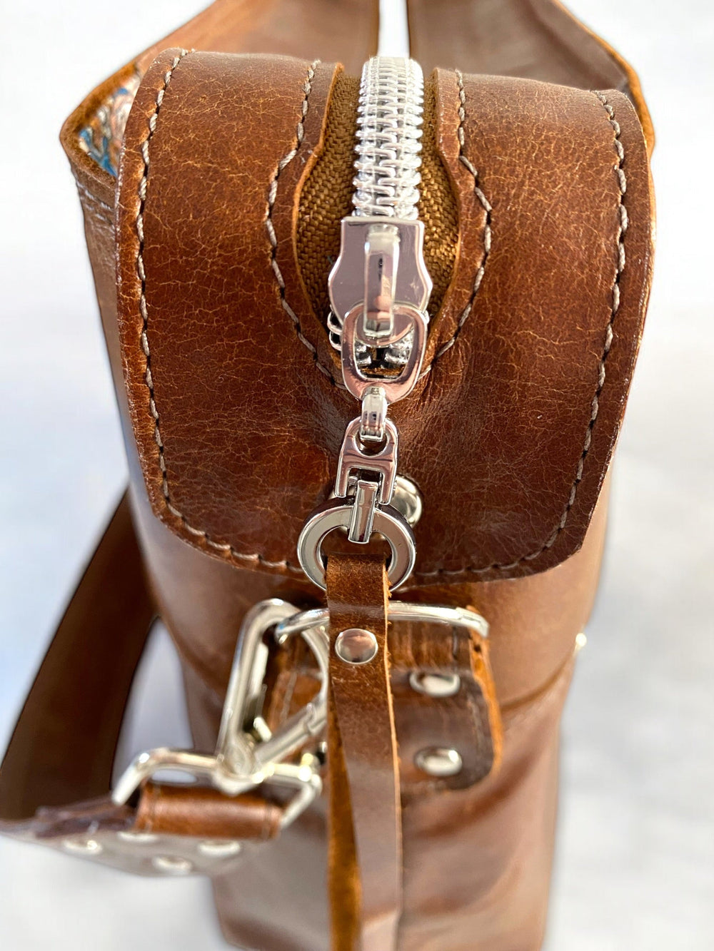 Close-up of a brown leather bag with zipper and strap details.
