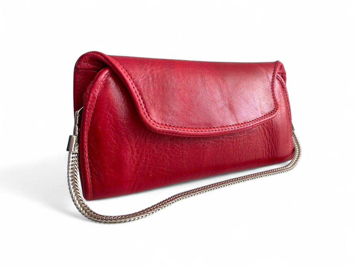 A red leather clutch with a silver chain handle and a magnetic closure, displayed against a white background.