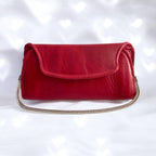 Red leather, Date Night clutch bag with a silver chain strap on a white background with a bokeh effect.