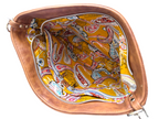 A brown leather handbag shown from a top-down view, highlighting its interior. The inside lining features a vibrant yellow background with a detailed paisley pattern in red, blue, and white.