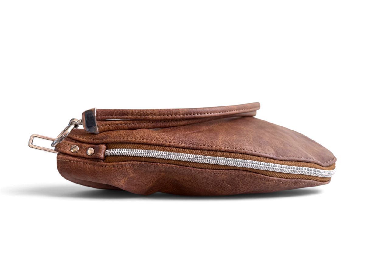 A brown leather handbag pouch shown in side profile, lying down on a clean white background.