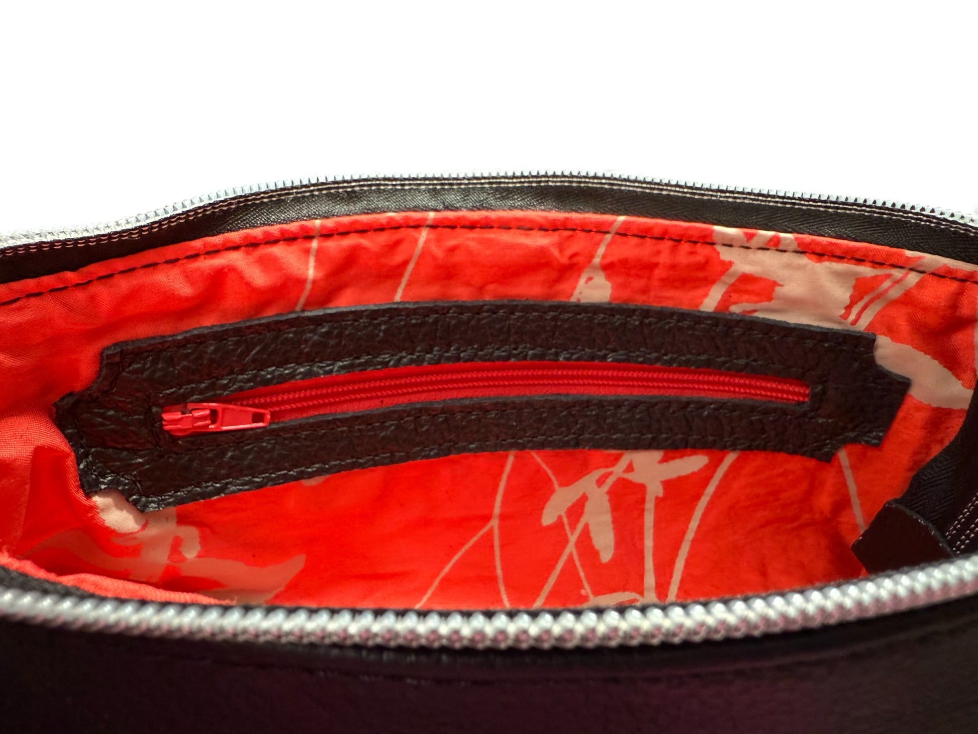 Close-up of the interior zipper pocket and red silk lining on the Ella clutch bag. Sustainable fashion accessory, exclusive to Lilly & Jude