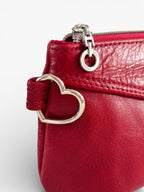 Red leather handbag with a heart-shaped clasp on a white background