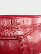 Close-up of a red leather bag with a Lilly & Jude logo on a light gray background