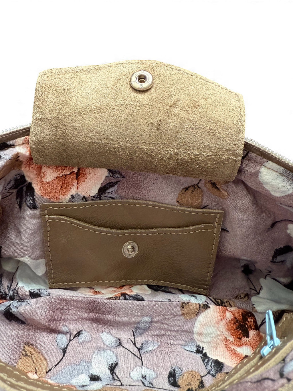 Close-up of a the interior of the beige Ella wristlet clutch bag, with floral patterned fabric lining. The image highlights the integrated leather purse 