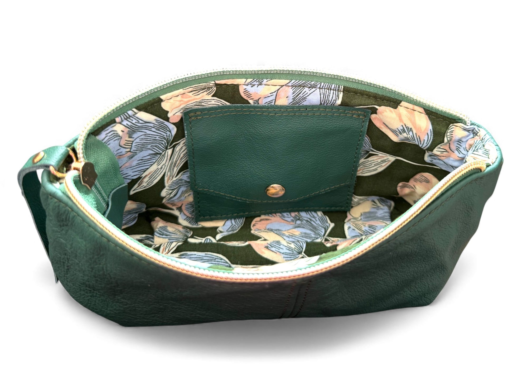 Interior view of the green Ella wristlet clutch bag, showing the green and blue floral patterned lining and leather, integrated purse. Exclusive to Lilly & Jude