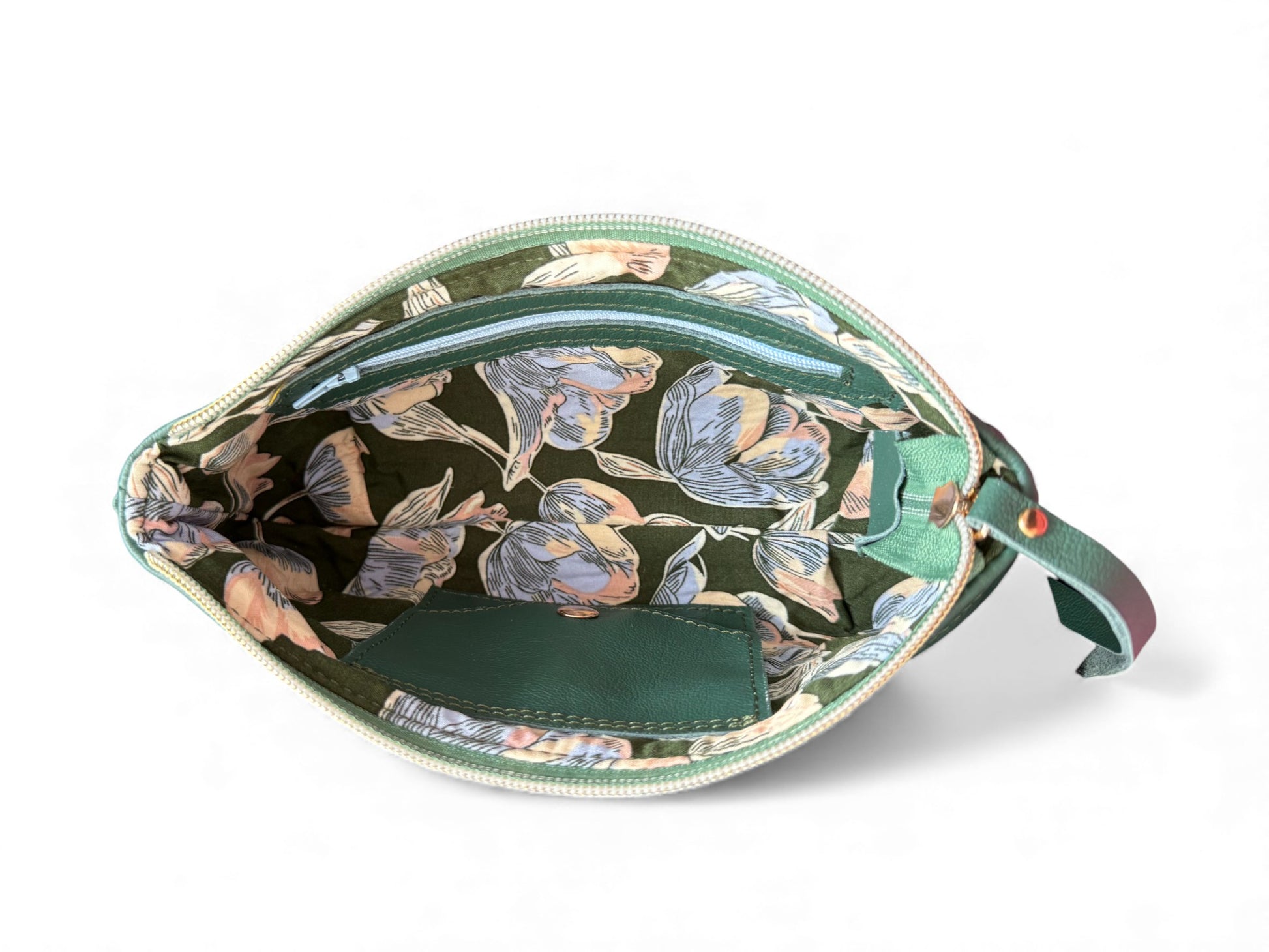 Interior view of the floral-patterned lining in the green Ella wristlet pouch  on a white background