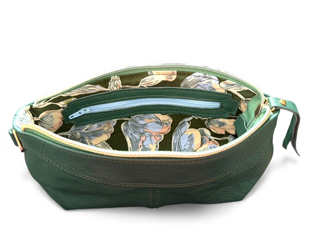 Interior view of the green Ella wristlet clutch bag, showing the green and blue floral patterned lining and leather trimmed interior zipper pocket. Exclusive to Lilly & Jude