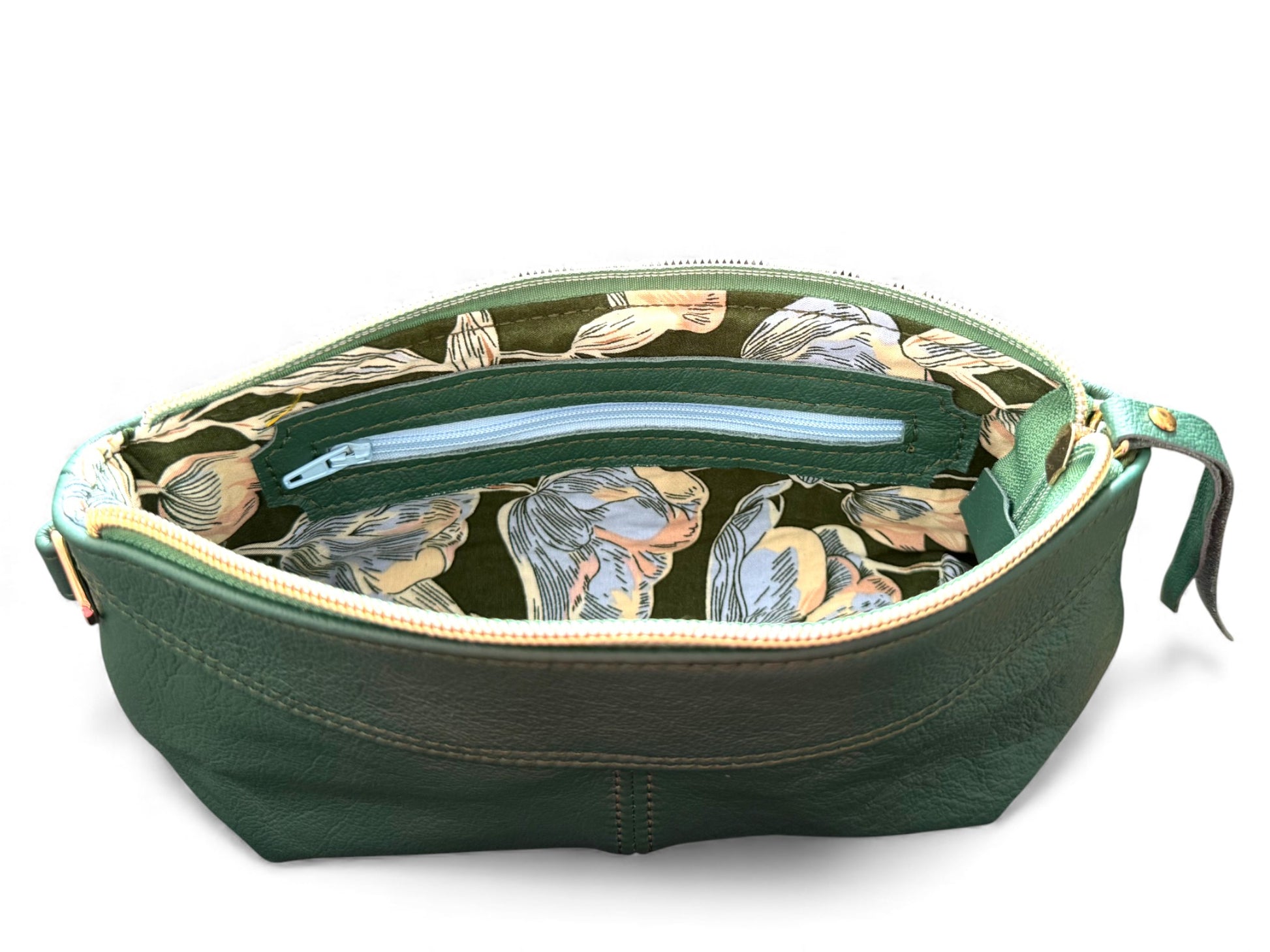 Interior view of the green Ella wristlet clutch bag, showing the green and blue floral patterned lining and leather trimmed interior zipper pocket. Exclusive to Lilly & Jude