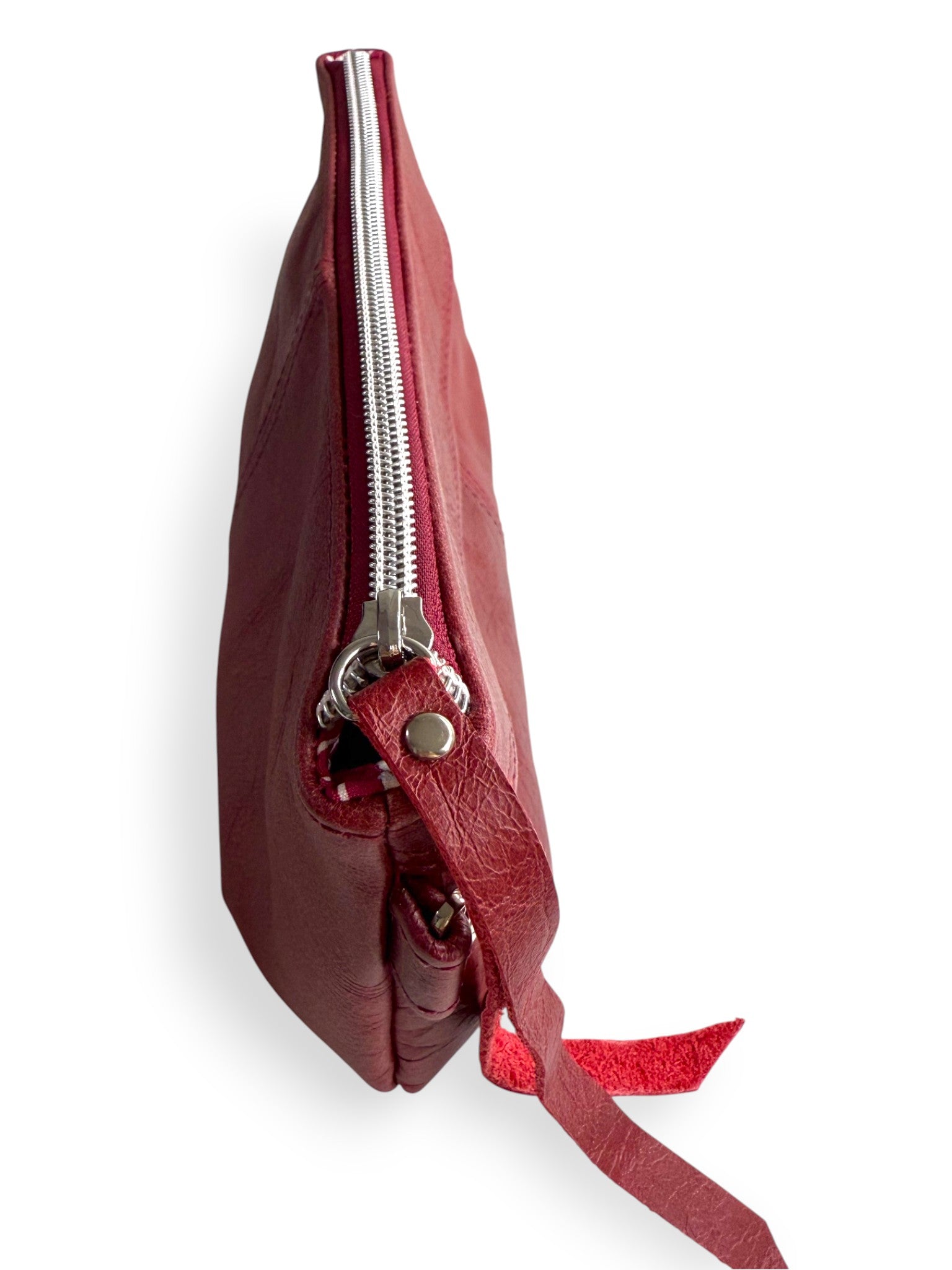 View from above of the Ella in deep red / burgundy leather bag with a silver zipper on a white background. 