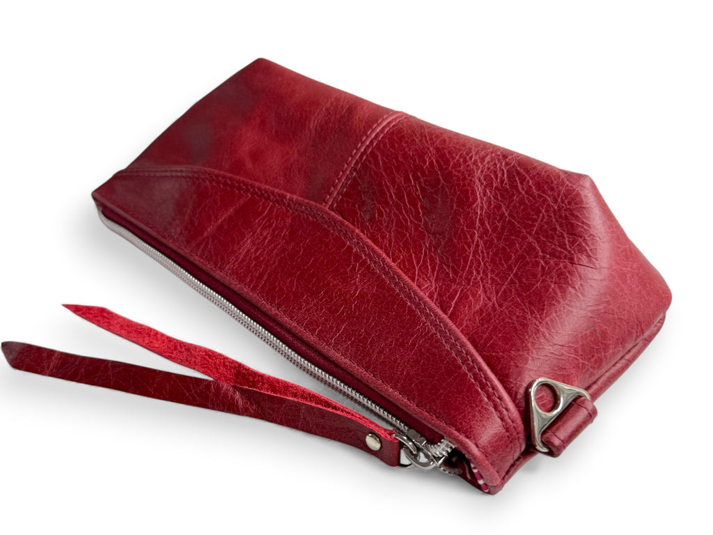Deep red leather Ella clutch lying on a white background. The image highlights the texture of the rescued leather 