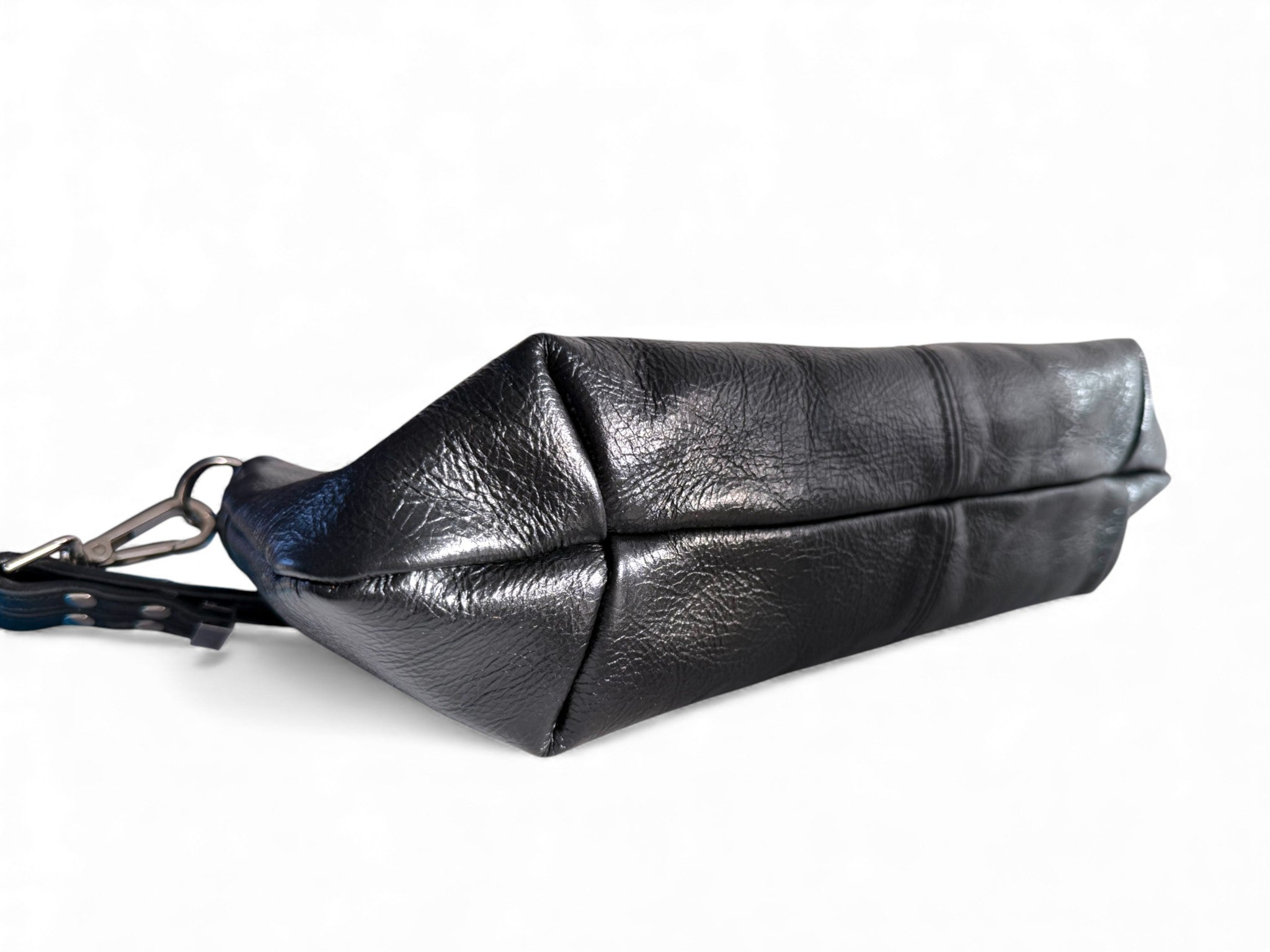 View of the bottom of the Elland Baguette style, black leather bag. The image shows the seams on the bottom of the handbag and the texture of the beautiful rescued leather. Exclusively made in the UK by Lilly & Jude 