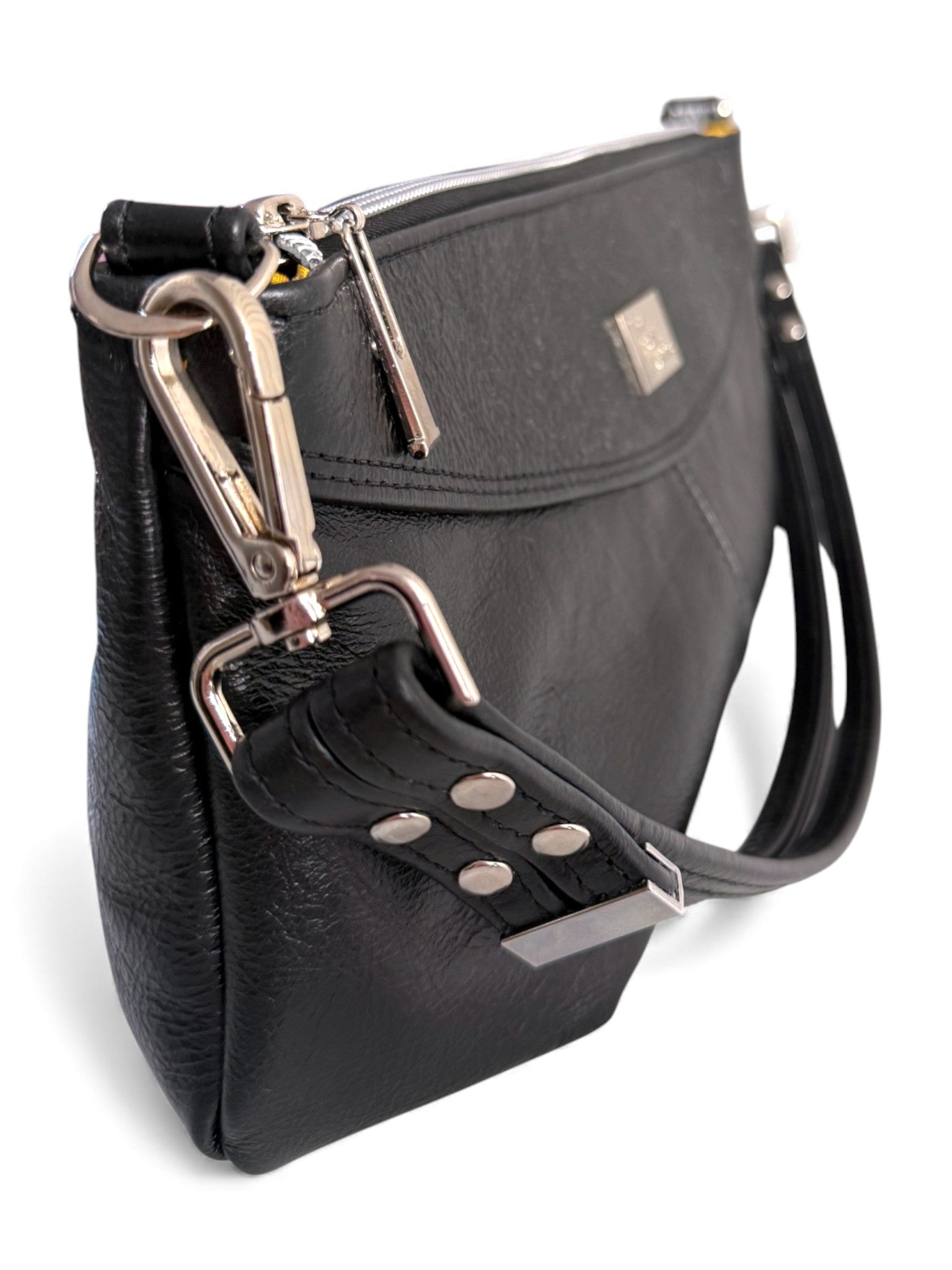 Side view of the Elland handbag, handmade using black, rescued leather. Image shows the detail of th silver hardware on a white background
