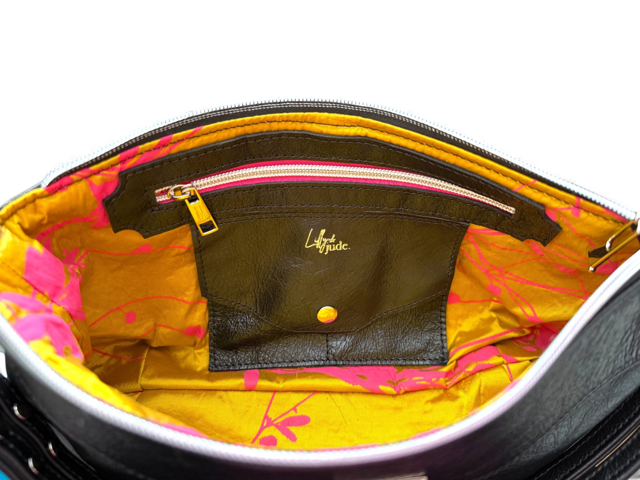 Close-up of a yellow gold and fuchsia pink bag patterned silk interior with a visible brand logo.The image shows the detail of the lining, including the leather trimmed zipper pocket and the integrated leather purse