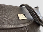Close up of the Elland. A dark grey leather handbag with a visible Lilly & Jude metal tag, on a white background