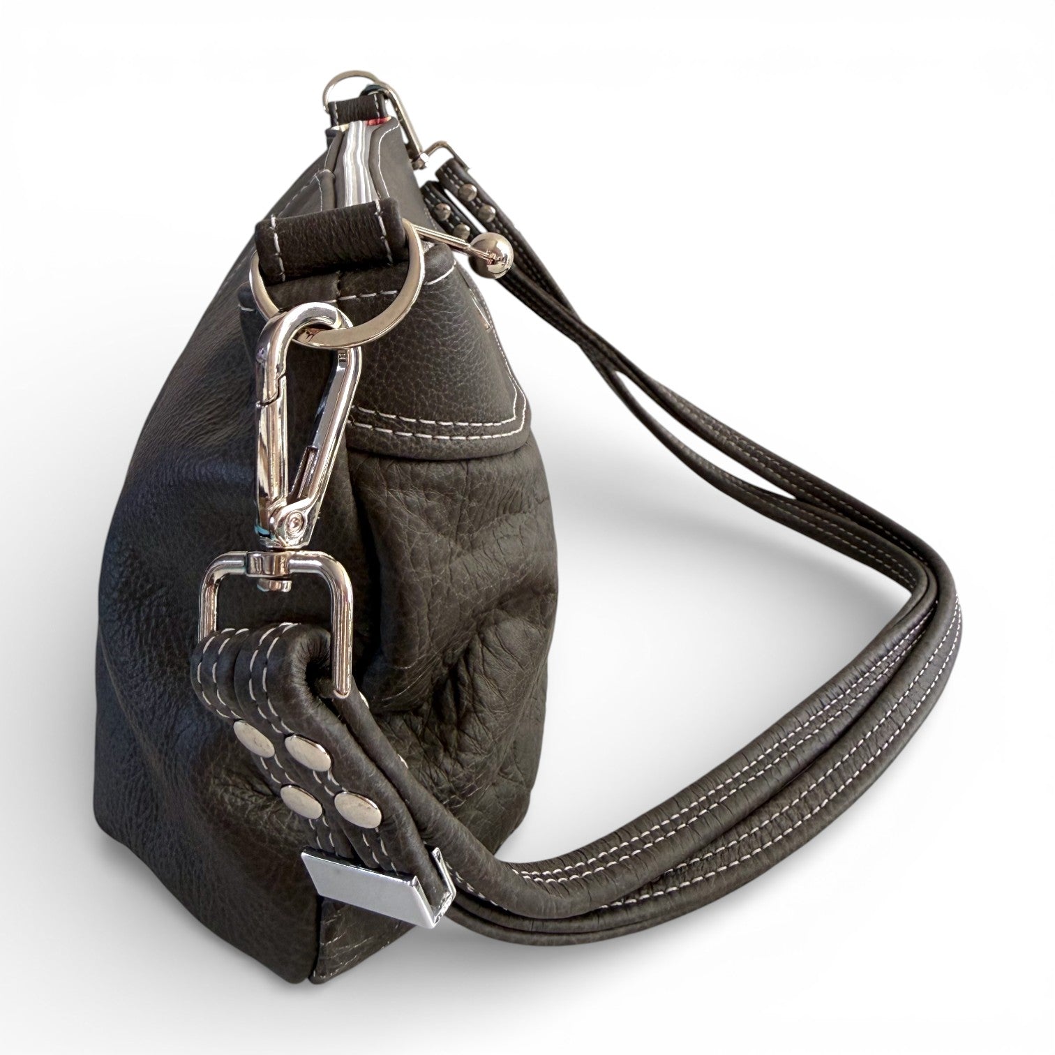 Side view of a dark grey leather handbag with metal hardware on a white background