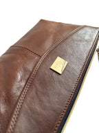 Close-up of a brown leather handbag with a gold Lilly & Jude tag on a white background