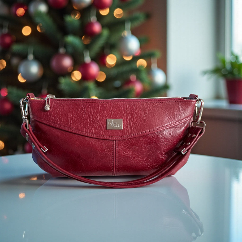 Red Elland, East/West handbag on a reflective surface with a Christmas tree in the background
