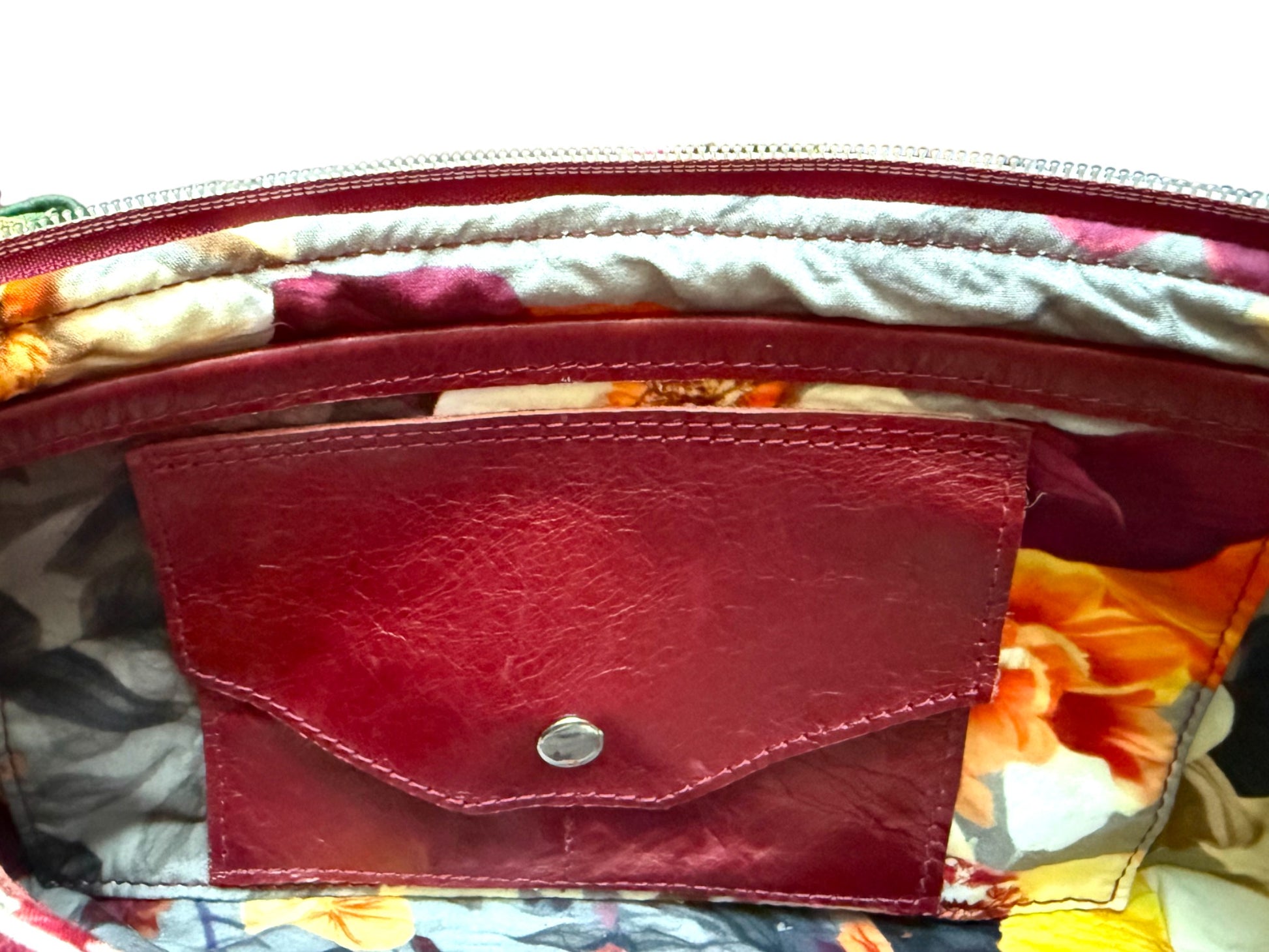 Close-up of a red leather integrated purse on the inside of the Elland Bag, on a colorful fabric background