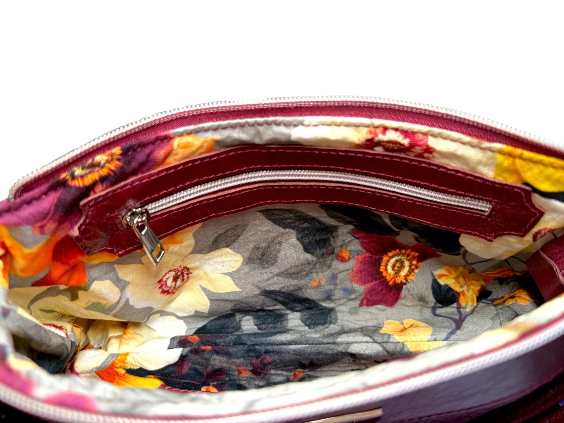 Floral-patterned bag lining with a leather trimmed zipper pocket on a white background