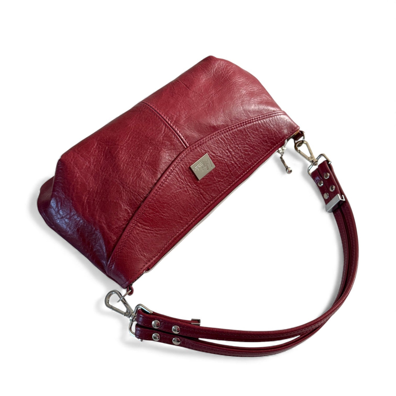 Red leather handbag with a strap, lying on a white background