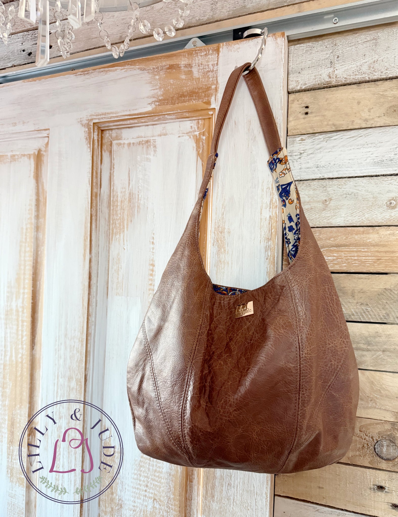 Brown, rescued leather handbag hanging on a wooden door with a rustic background