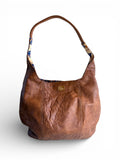 Brown, distressed, genuine leather handbag with paisley patterned interior on a white background