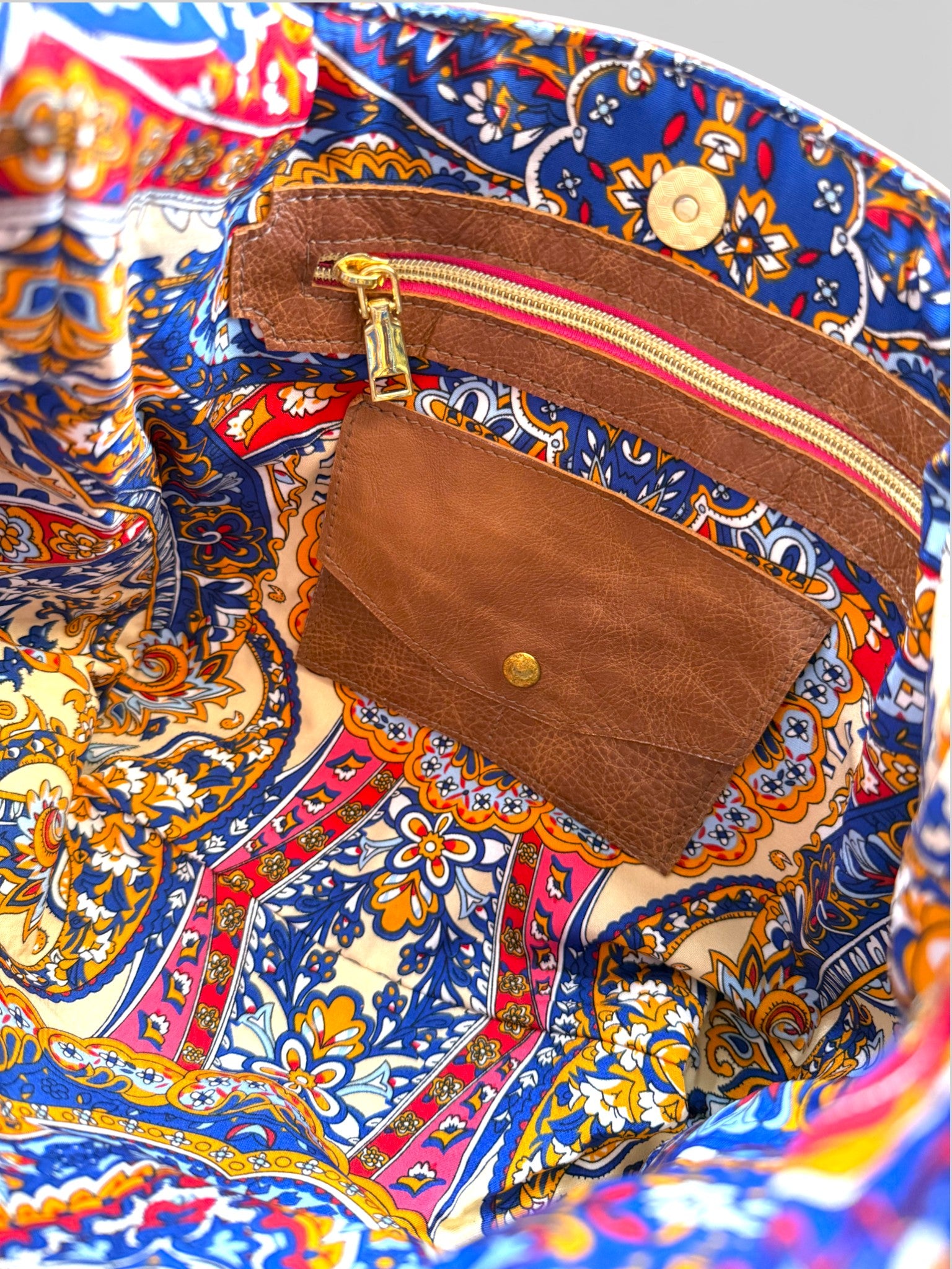 Interior view of the bag, highlighting the beautiful paisley style lining, integrated leather purse / wallet and the leather trimmed zipper pocket.