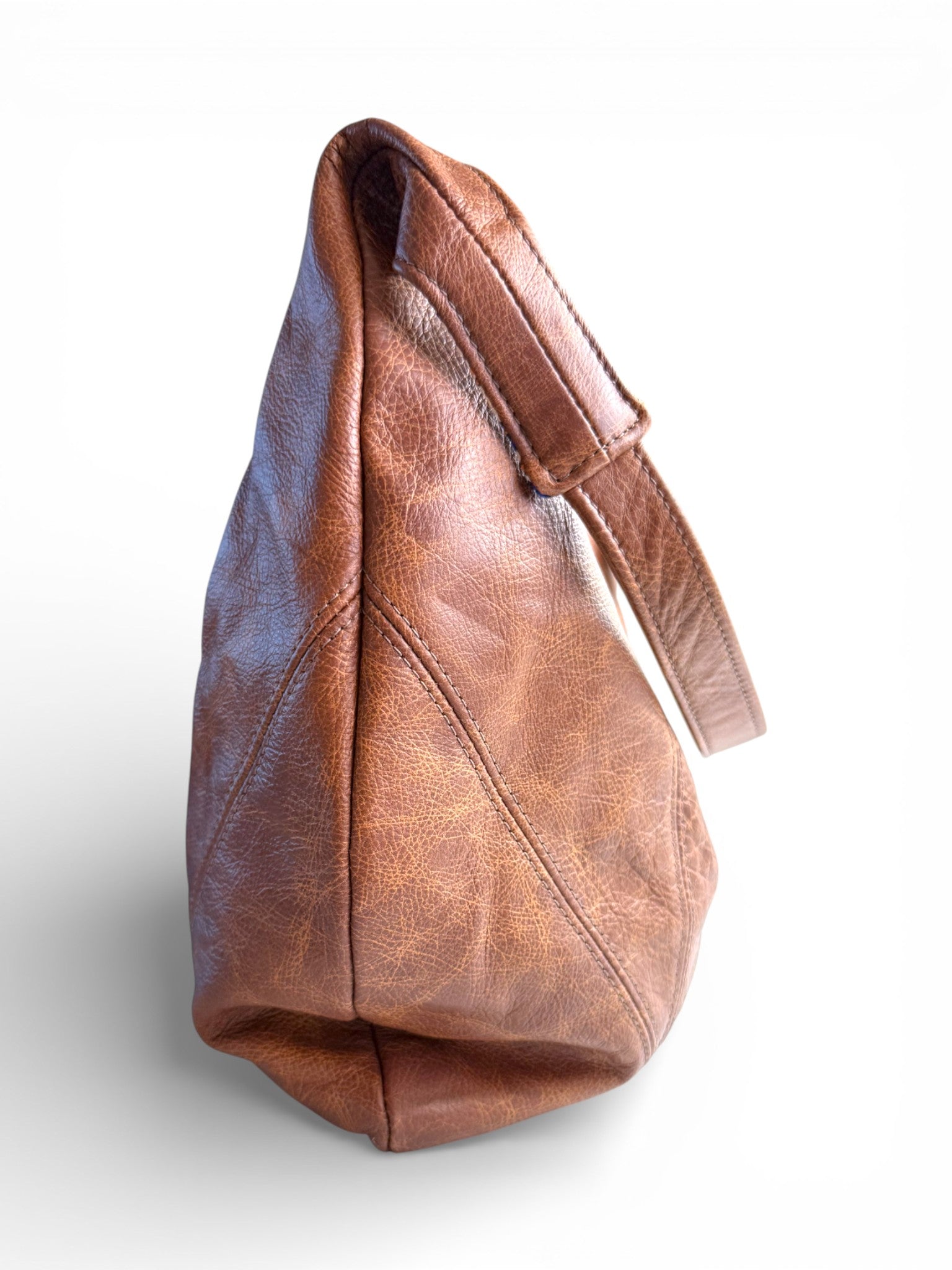 Side on view of a brown leather slouchy handbag on a white background
