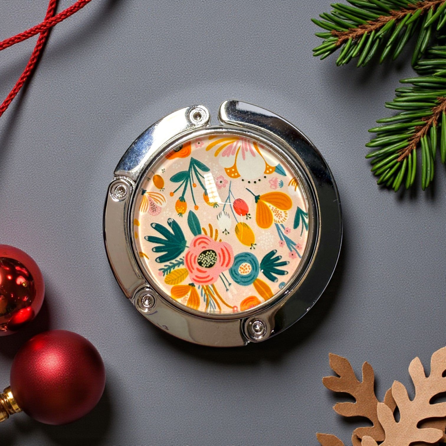 Round floral-patterned handbag holder on a grey background with Christmas decorations.