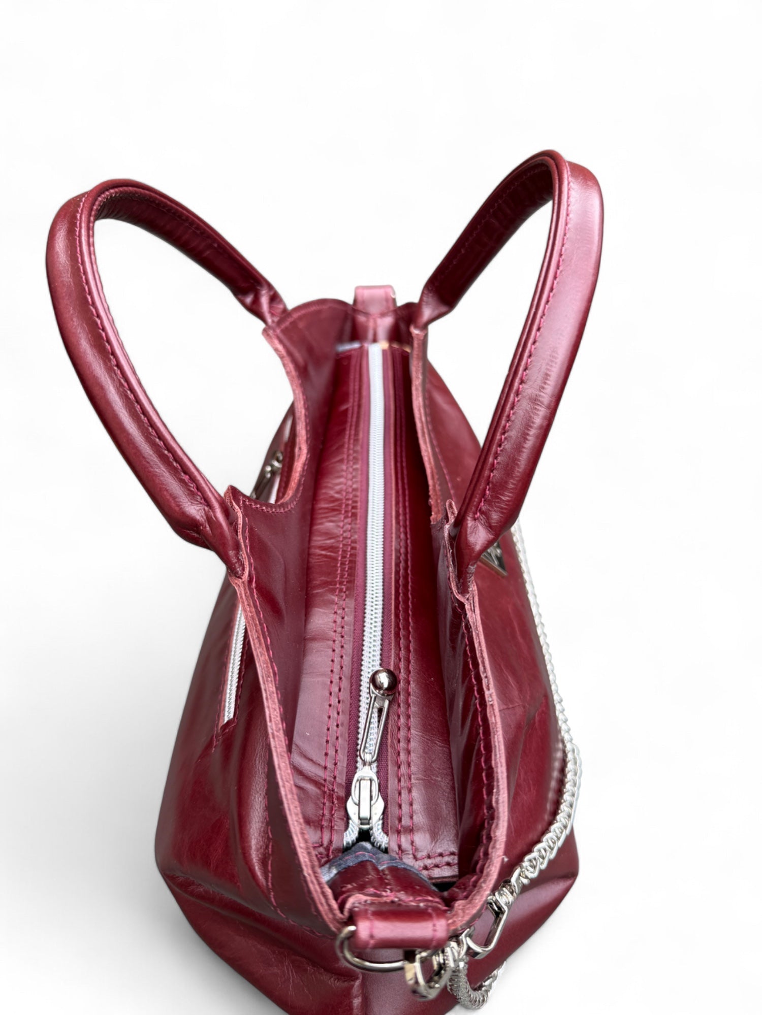 Top view of the deep berry coloured leather handbag, showing the zipper opening. This Eco conscious handbag, Flossy is sat on a white background