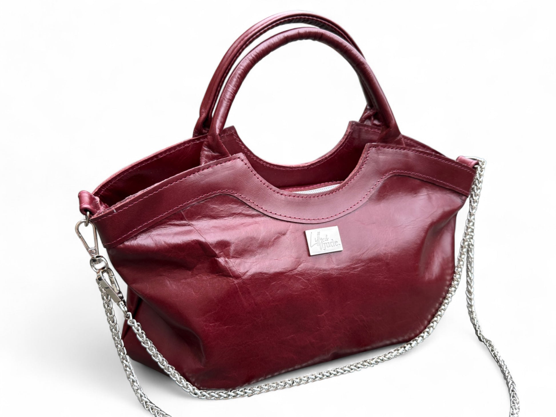 Burgundy leather handbag, with leather handles and a long, silver chain. The image shows the perfect imperfections in the leather